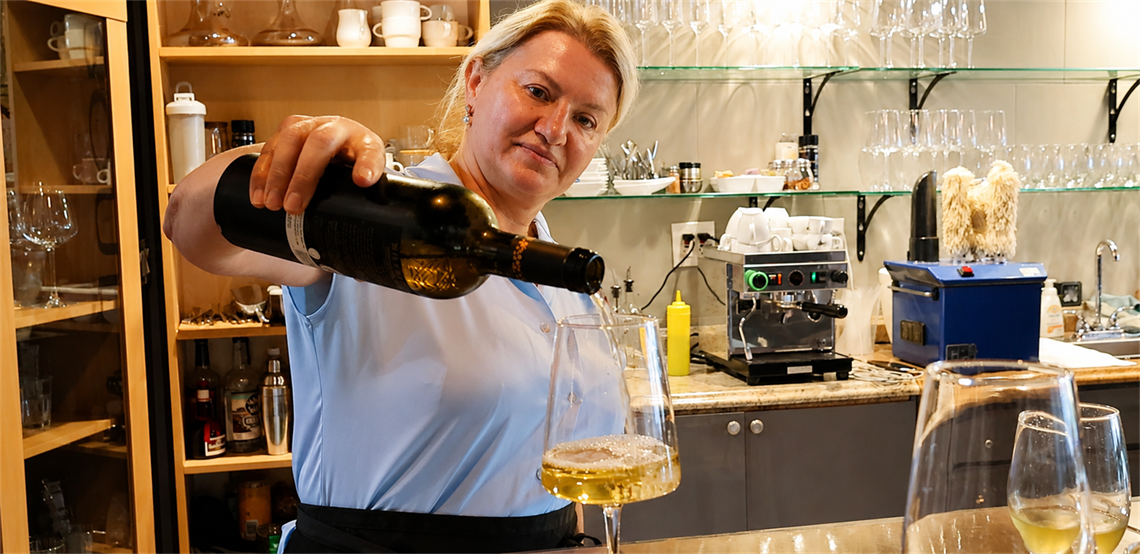 Natalya at Soul Sicilian poring white wine.