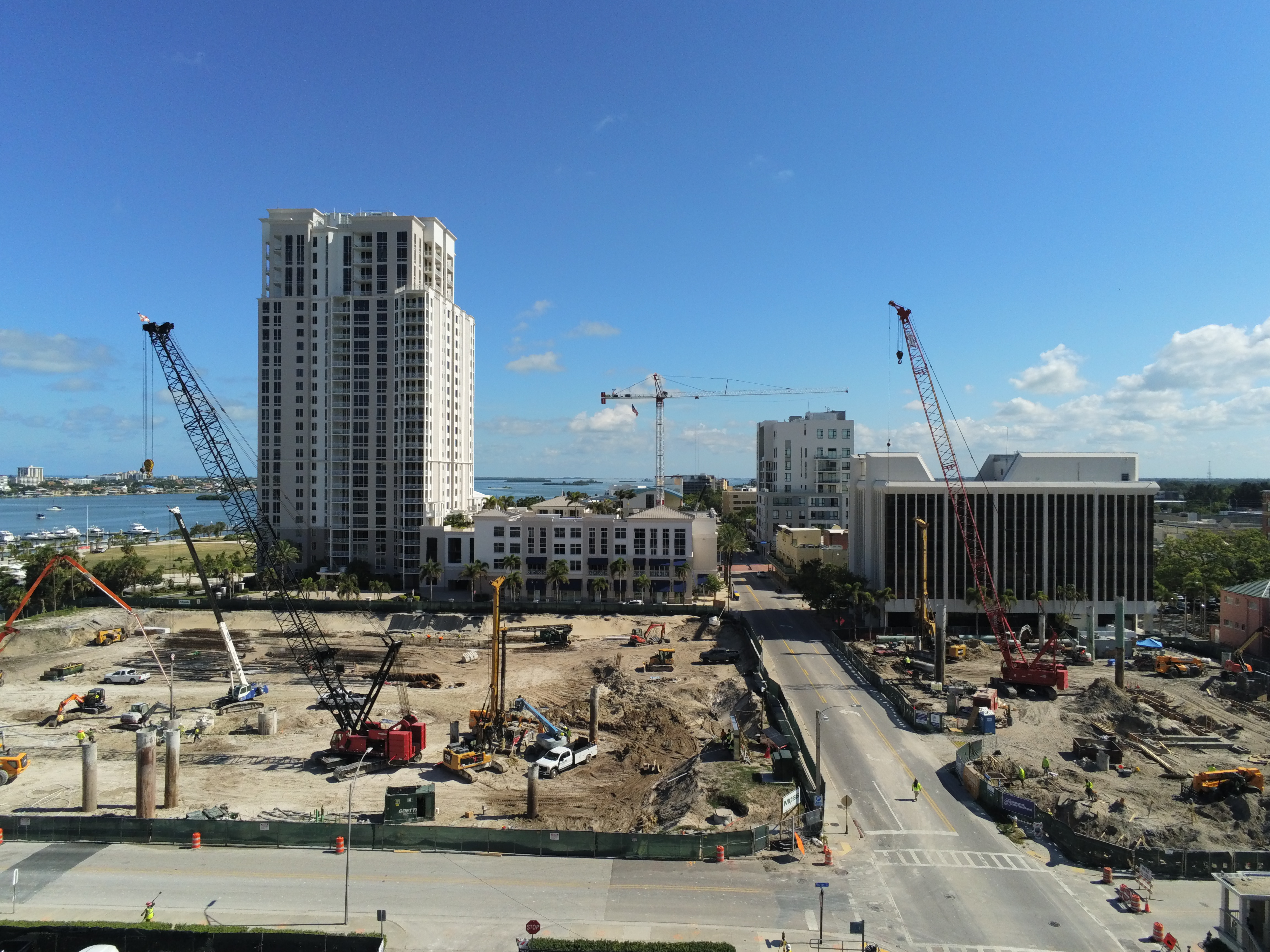 Aerial view of a large construction site in Downtown Clearwater, featuring cranes, construction equipment, surrounding high-rise buildings, and ongoing development.